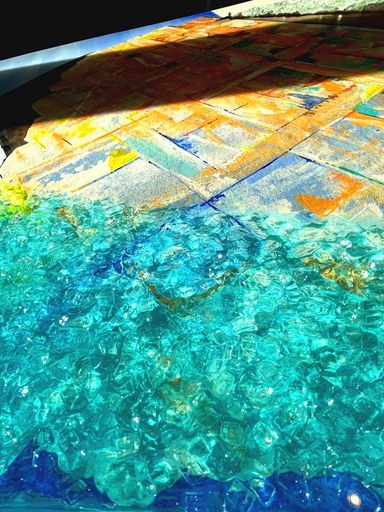 ESG - Sicherheitsglassplitt in transparentem, leicht türkies eingefärbten Kunstharz wirkt -sehr nah betrachtet- wie flüssig auf Ultramarin.